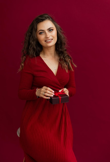 Retrato de mulher emocional de vestido vermelho abriu caixa com listra e feliz sorrindo para a câmera