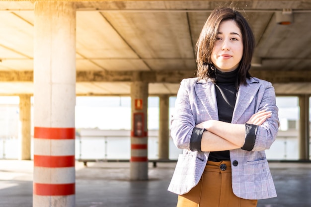 Retrato de mulher empresária em traje formal com braços cruzados ao ar livre Jovem em traje formal de braços cruzados ao ar livre