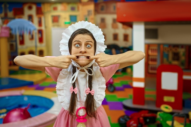 Retrato de mulher engraçada vestindo como bebê recém-nascido fazendo careta para a câmera mostrando os dentes