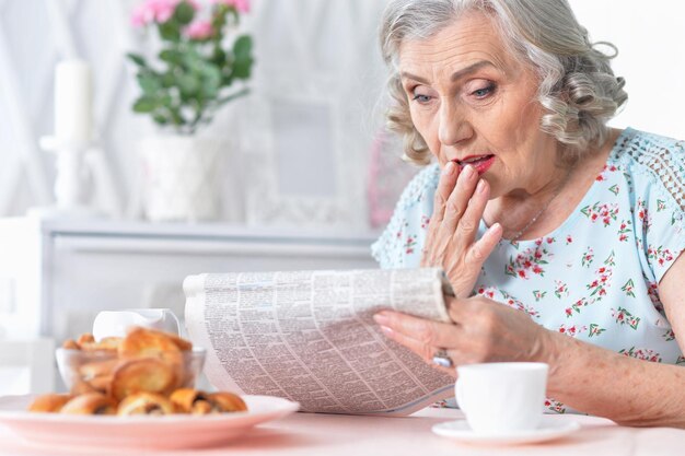 Retrato de mulher envelhecida pensativa lendo jornal