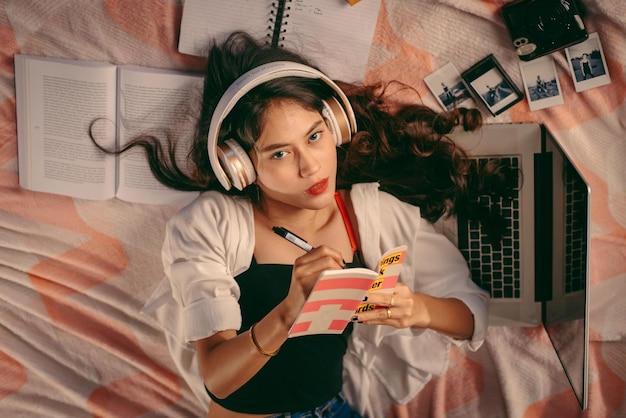 Foto retrato de mulher escrevendo em diário enquanto está deitada em casa