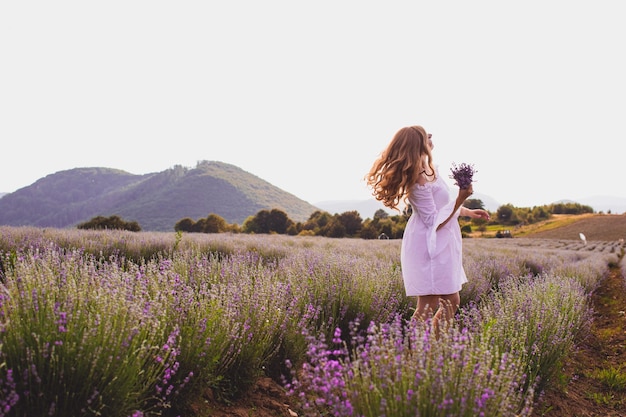 Retrato de mulher está de pé entre as plantações de lavanda