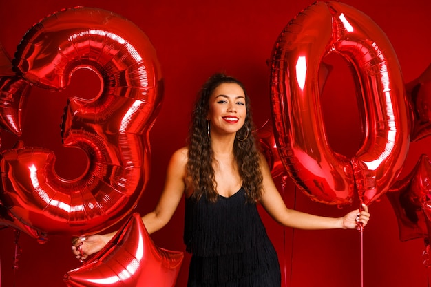 Retrato de mulher feliz ano de idade em fundo vermelho com balões vermelhos, uma linda garota de caucasiano.