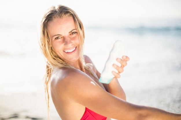 Retrato de mulher feliz, aplicar loção protetor solar na praia