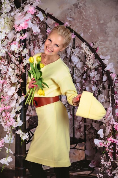 Retrato de mulher feliz atraente em vestido de primavera segurando tulipas amarelas