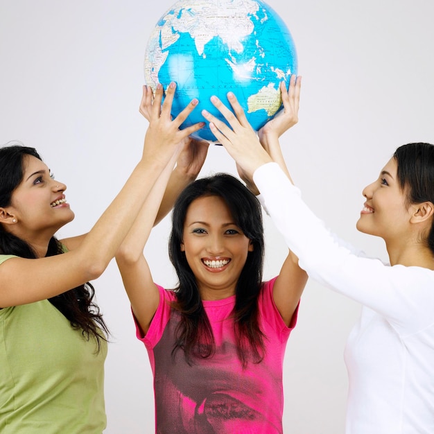 Retrato de mulher feliz com amigos segurando um globo contra fundo branco