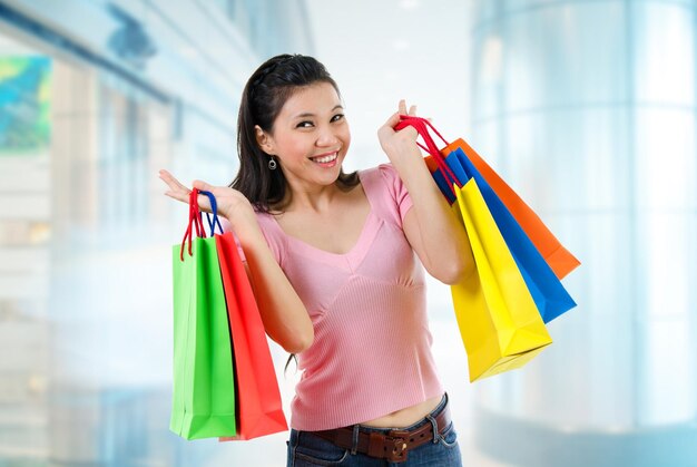 Retrato de mulher feliz com sacos de compras de pé na calçada