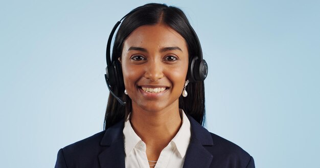 Retrato de mulher feliz e fones de ouvido para call center ou telemarketing contra um fundo de estúdio azul Rosto de consultora ou agente sorridente com microfone para aconselhamento on-line sobre espaço de maquete