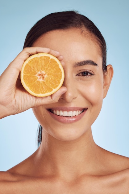 Foto retrato de mulher feliz e laranja para dieta de vitamina c ou cuidados com a pele contra um fundo de estúdio azul sorriso de pessoa do sexo feminino com frutas cítricas orgânicas para dermatologia de nutrição natural ou tratamento facial