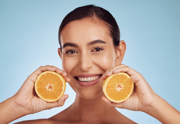 Retrato de mulher feliz e sorriso com cuidados com a pele de vitamina C laranja ou dieta contra fundo de estúdio azul Pessoa do sexo feminino com frutas cítricas orgânicas para dermatologia de nutrição natural ou bem-estar saudável