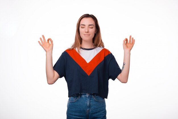 Retrato de mulher feliz hipster meditando sobre parede branca