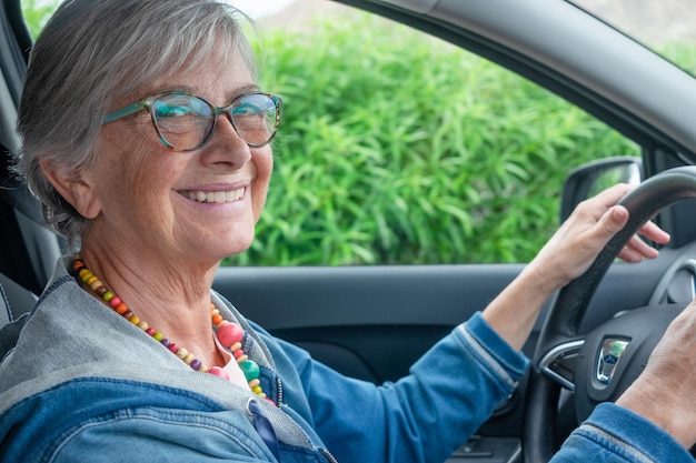 Retrato de mulher feliz sênior com óculos, dirigindo carro