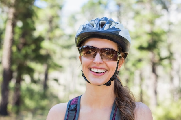 Retrato de mulher feliz usando capacete na floresta