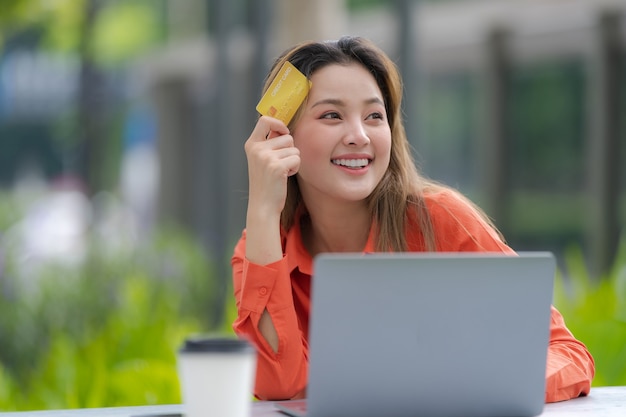 Retrato de mulher feliz usando laptop com cartão de crédito e rosto sorridente no parque do shopping