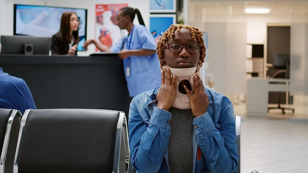 Retrato de mulher ferida com colar cervical no saguão da sala de espera, sentado na recepção do hospital para atender a consulta com o médico. Pessoa com lesão usando espuma de pescoço médica.