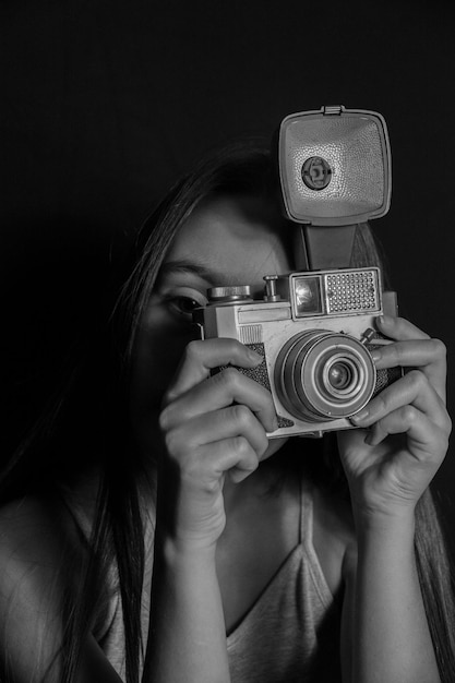 Foto retrato de mulher fotografando contra fundo preto