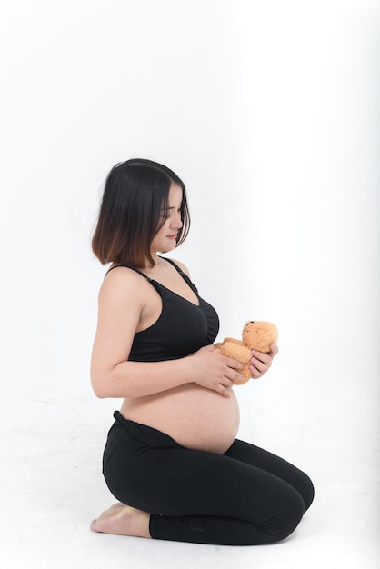Retrato de mulher grávida asiática em fundo branco boneca de urso de pelúcia de tailândia na mão