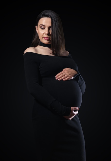 Retrato de mulher grávida de vestido preto em fundo preto com espaço de cópia