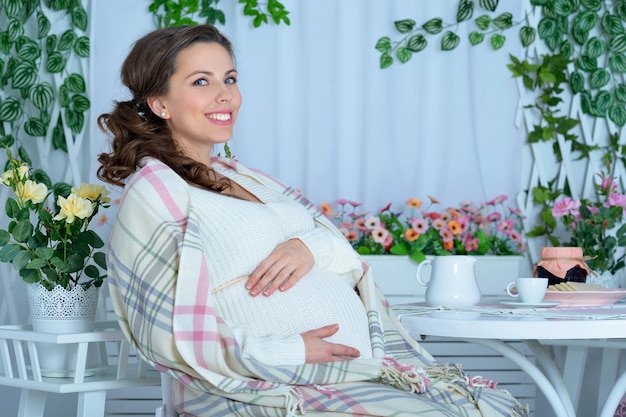Retrato de mulher grávida sorridente feliz sentada à mesa