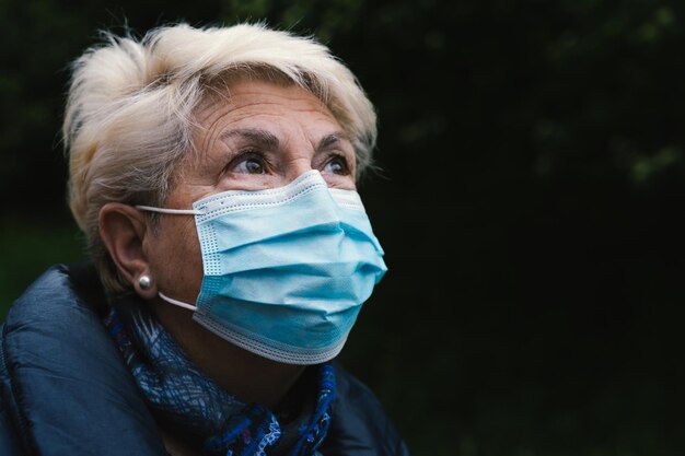 Retrato de mulher idosa com máscara azul Mulher idosa com rosto cobrindo com olhar pensativo