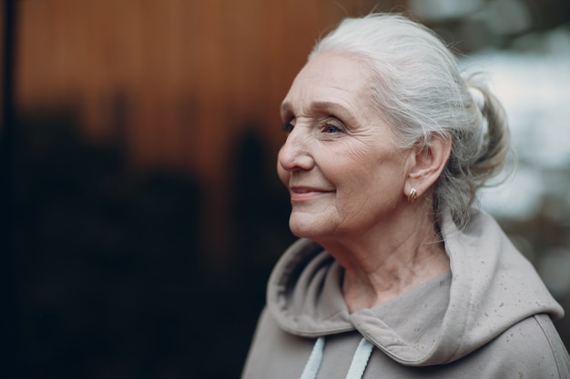 Retrato de mulher idosa de cabelos grisalhos madura ao ar livre.