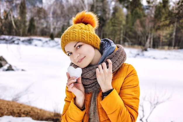 retrato de mulher jovem adulta feliz na natureza com um coração de neve nas mãos