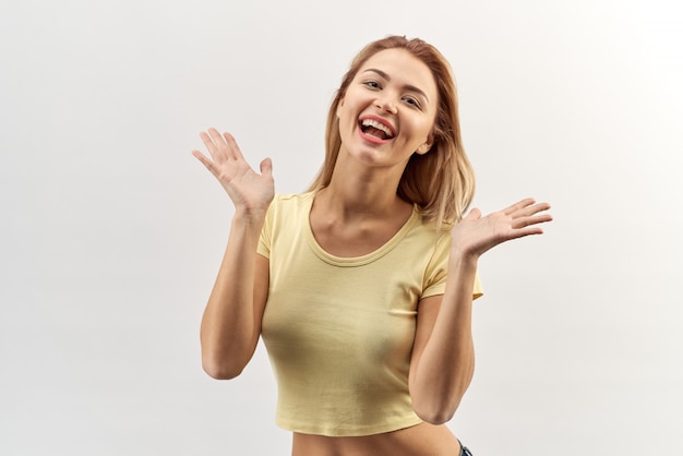 Foto retrato de mulher jovem alegre feliz na camisa amarela com emoções arrebatadoras e uma distribuição de mãos dadas e aplaudindo.