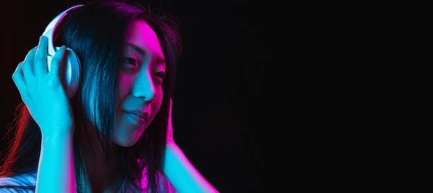 Retrato de mulher jovem asiática na parede escura em néon conceito de emoções humanas expressão facial anúncio de vendas para jovens