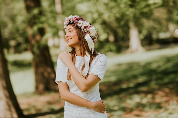 Retrato, de, mulher jovem, com, grinalda, de, flores frescas, ligado, cabeça, parque