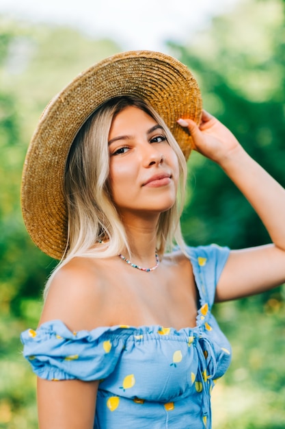 Retrato de mulher jovem e atraente com chapéu de palha ao ar livre em dia ensolarado de verão.