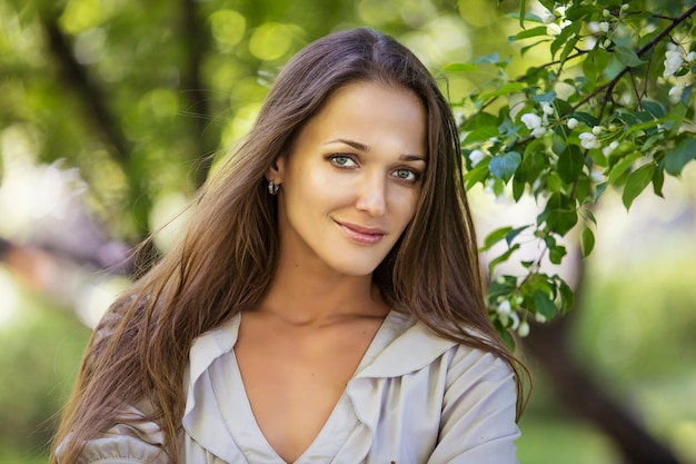 Retrato de mulher jovem e bonita ao lado de um galho de uma macieira em flor no parque ao ar livre