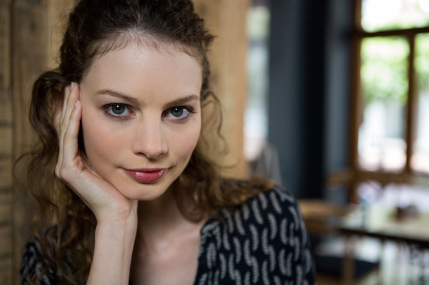 Retrato de mulher jovem e bonita com a mão no queixo em um café