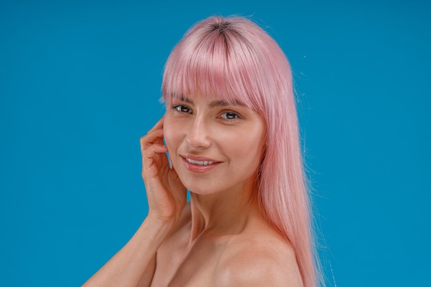 Retrato de mulher jovem e bonita com cabelo rosa e pele perfeita, sorrindo para a câmera posando isolado