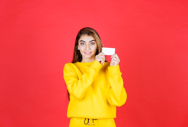 Retrato de mulher jovem e bonita com cartão de visita em branco em pé