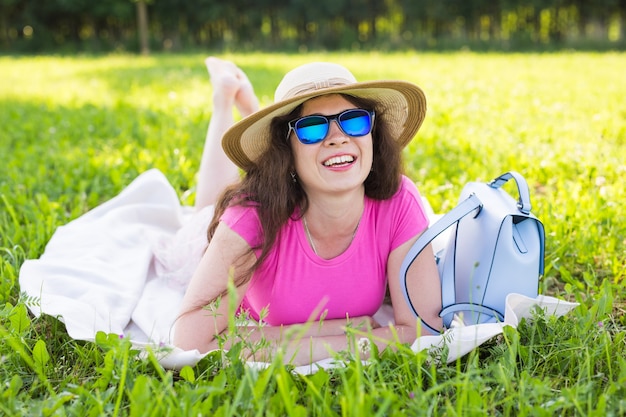 Retrato de mulher jovem e bonita com chapéu e óculos de sol no parque no piquenique