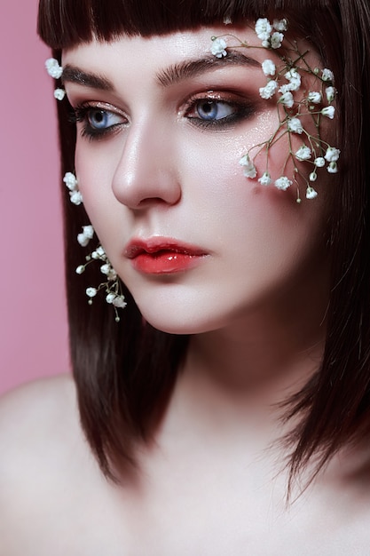 Retrato de mulher jovem e bonita com flores no rosto. maquiagem estilo coreano, beleza de boneca