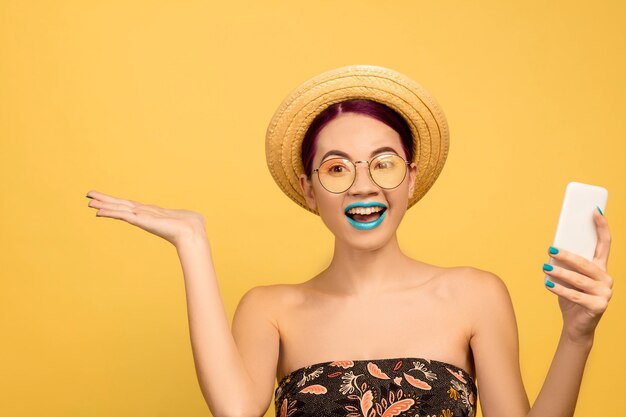 Retrato de mulher jovem e bonita com maquiagem brilhante isolado no fundo amarelo do estúdio