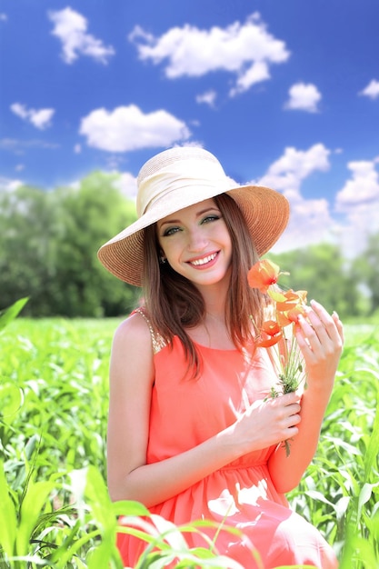 Retrato de mulher jovem e bonita com papoulas no campo