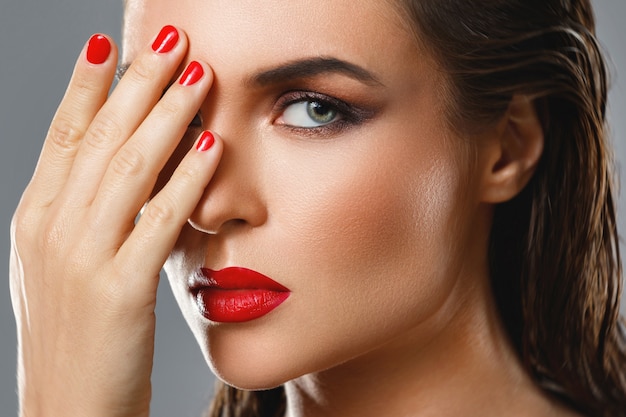 Retrato de mulher jovem e bonita com um batom vermelho e esmalte