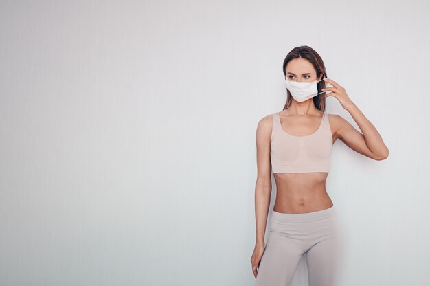 Retrato de mulher jovem e bonita no sportswear usando máscara protetora