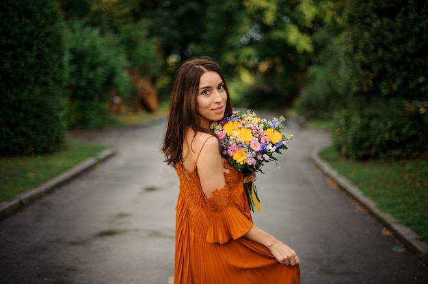 Retrato de mulher jovem e bonita no vestido longo laranja