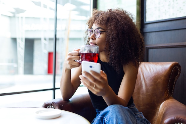 Retrato de mulher jovem e bonita tomando café no café.