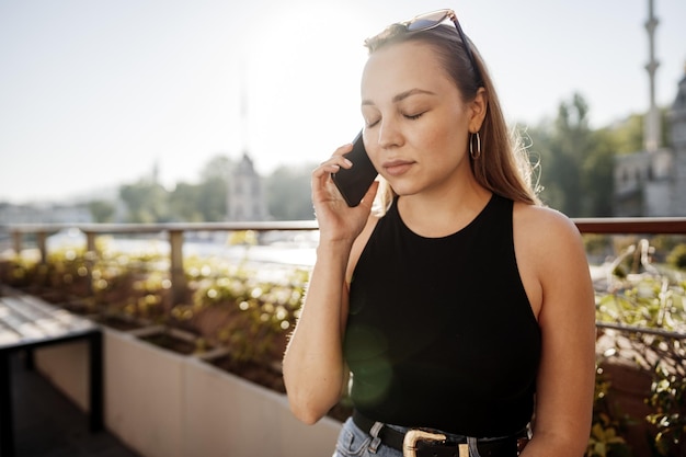 Retrato de mulher jovem e bonita usando smartphone no terraço ao ar livre em Istambul