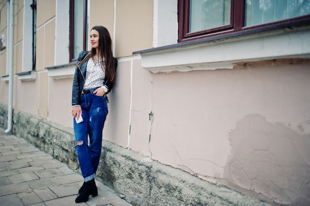 Retrato de mulher jovem elegante vestindo jaqueta de couro com o celular na mão