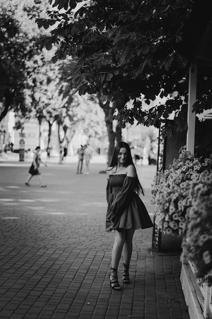 Retrato de mulher jovem feliz com vestido azul rindo olhando para a câmera em pé na rua