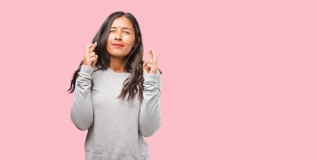 Retrato de mulher jovem indiano, cruzando os dedos, deseja ter sorte para o projeto futuro