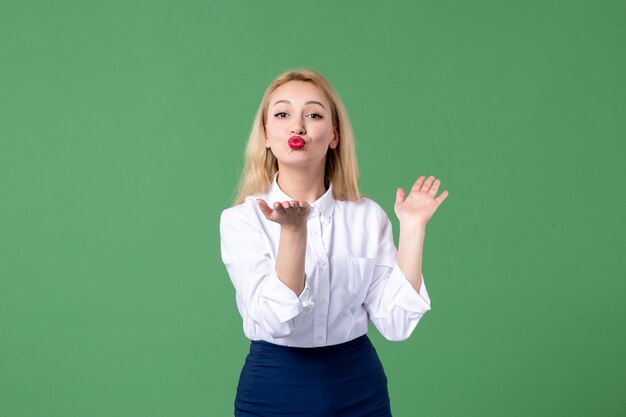 retrato de mulher jovem mandando beijos em roupas conservadoras parede verde aula escola aluno professor estudo