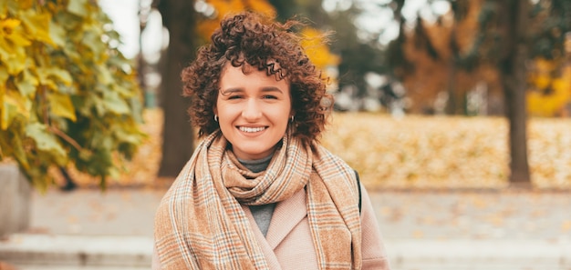 Retrato de mulher jovem sorridente com casaco e cabelo encaracolado