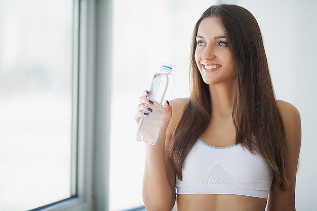 Retrato de mulher jovem sorridente e feliz com garrafa de água fresca