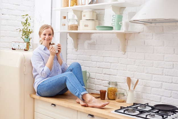 Retrato de mulher jovem sorridente na cozinha moderna